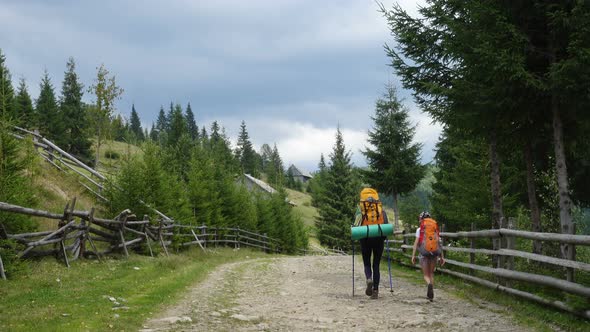 Mother And Daughter Backpackers Walking By The Ground Rural Road