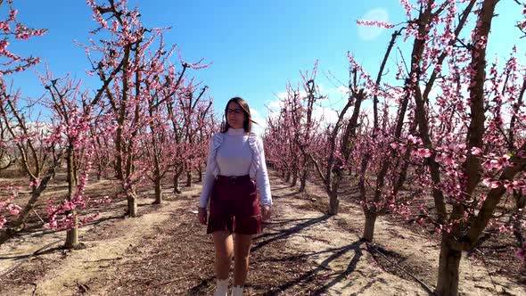 Cute young woman walks through almond trees in blossom in Cieza, Spain.