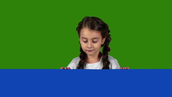 Child Looks Out From Behind a Blue Board and Shows a Thumbs Up. Green Screen. Slow Motion