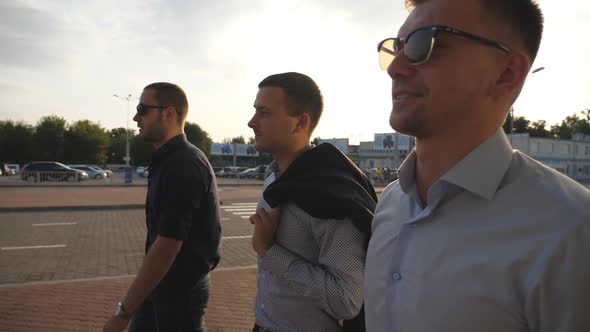 Three Young Businessmen Walking in City with Sun Flare at Background. Business Men Commuting To Work