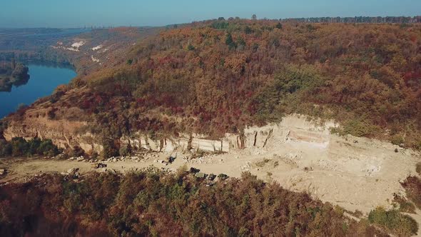 View on the work of equipment in the sand quarry on the background of the forest near the river.