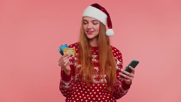 Girl in Christmas Sweater Using Credit Bank Card Smartphone Transferring Money Shopping Online