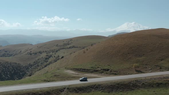 Off Road Car Driving in Winding Road Through Highlands and Field on Snowy Mountain Peak Landscape