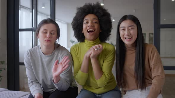 Video Call POV of Three Cheerful Multiethnic Women Waving and Smiling at Webcamera