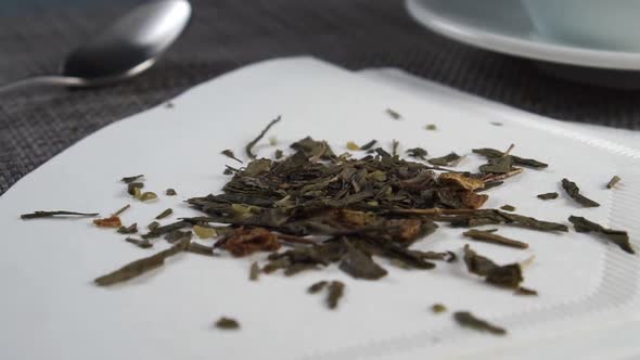 Herbal green dried hemp tea falls on a white paper empty new filter bag on a kitchen mat