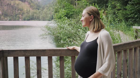 Pregnant Woman Walking Along Terrace Near the Mountain Lake