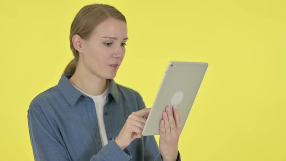 Young Woman Celebrating Success on Tablet on Yellow Background