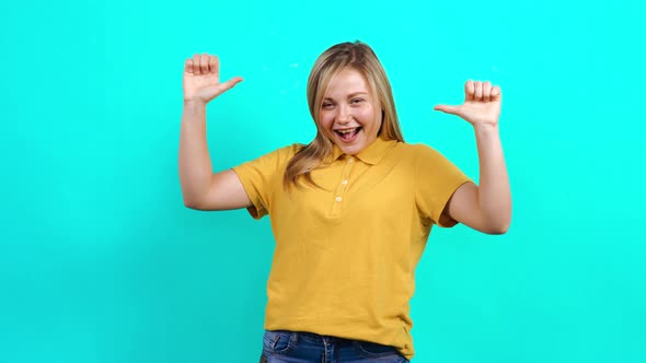 The Happy Young Woman Recommends Herself with Both Tongues Looking Into the Room.