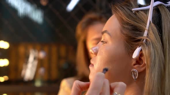 Makeup Artist Doing Makeup to Young Woman with Concealer in Beauty Salon