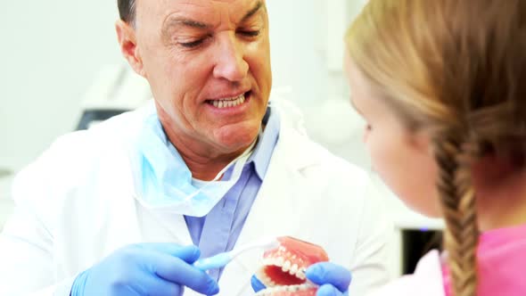 Dentist showing young patient how to brush teeth