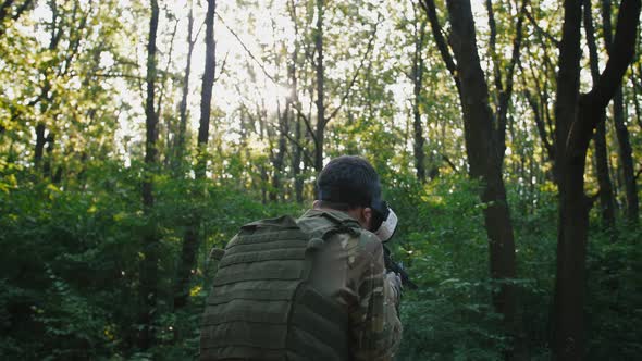 Soldier with Rifle Wearing Virtual Reality Glasses Outdoors