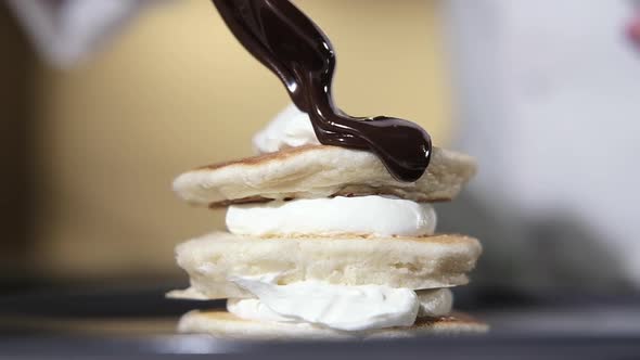 chef pours hot chocolate syrup from spoon over sweet dessert