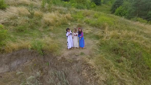 Aerial View of Three Girlfriends Having Fun and Laughing Standing on a High Hill at the River