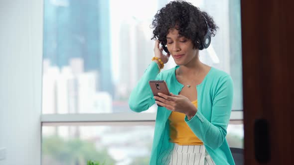 Young Black Woman Listening To Music Using Bluetooth Headphones Headset with Mobile Phone