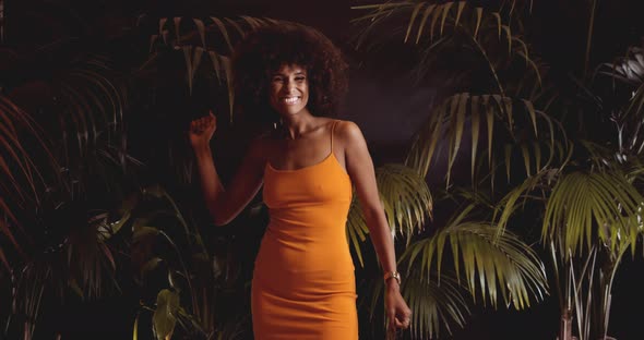 Young Laughing Woman With Afro In Orange Dress Dancing To Camera