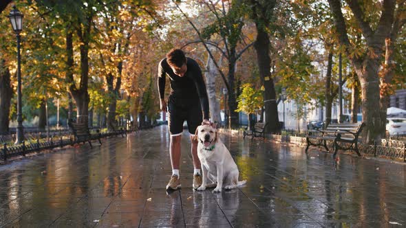 Portrait of Young Black Man and His White Labrador Dog in City Park During Beautiful Autumn Morning