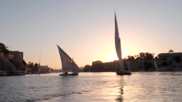 View of two feluccas during sunset sailing on the Nile river in Aswan, Egypt.