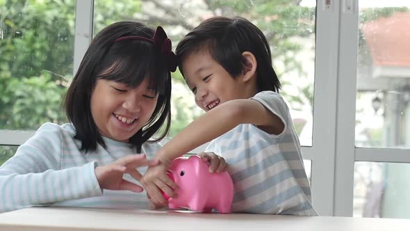 Cute Asian Child Putting A Coin In To A Piggy Bank Slow Motion