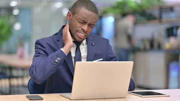 Tired African Businessman with Laptop Having Neck Pain in Office