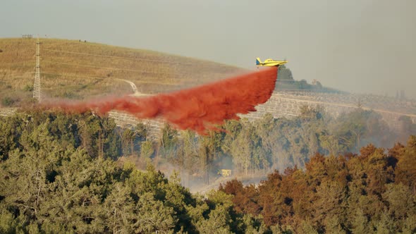 Fire fighter plane drops fire retardant on a forest fire in the hills