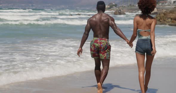 Couple walking together on beach in the sunshine 4k