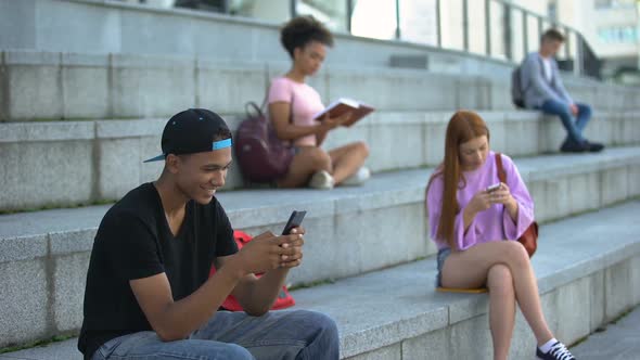 Joyful Male Teenager Chatting Smartphone Outdoors, High School Students on Break