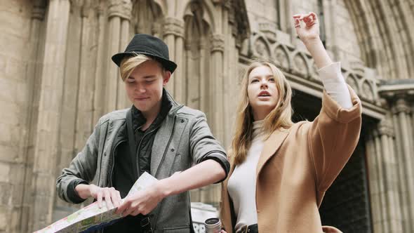 Two Stylish Friend Standing at the Street and Look for Something Using a Map