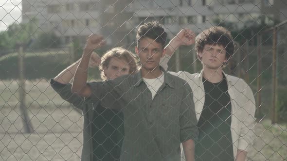 Three Serious Young Men Shaking Clenched Fists and Looking at Camera. Portrait of Group of