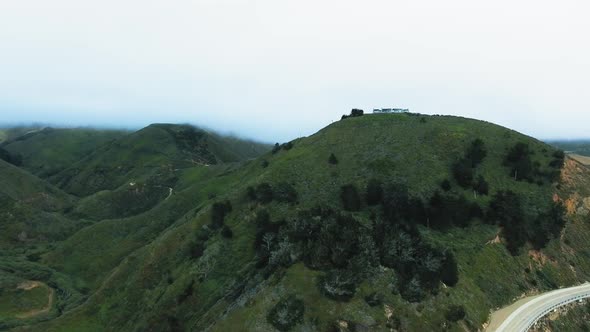 Aerial footage of green mountains, roads and houses on top of the mountain (California, USA)