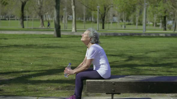 Tired Elderly Woman Resting After Workout in Park