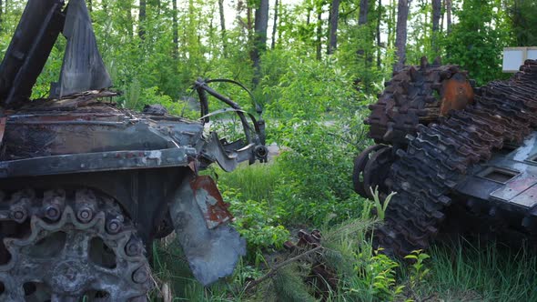 Closeup Parts of Destroyed Military Vehicles with Suburban Road and Green Forest at Background