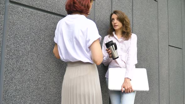 Two Successful Businesswomen are Talking About a the Project While Standing Near the Wall Outside