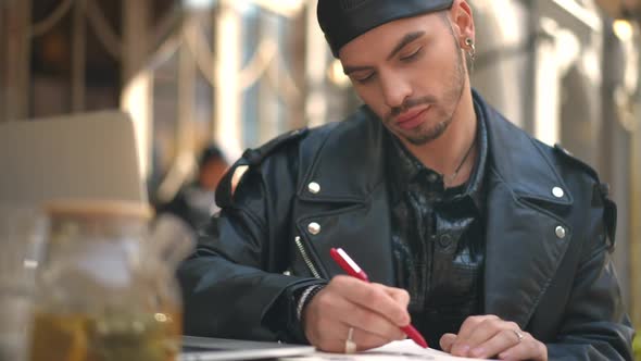 Front View Portrait of Focused Caucasian Talented LGBTQ Man Painting Sketch Sitting on City Street