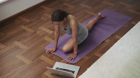 African Woman doing yoga exercise on laptop and does it