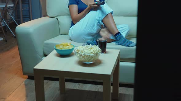 Woman Holding Remote Control and Eating Popcorn