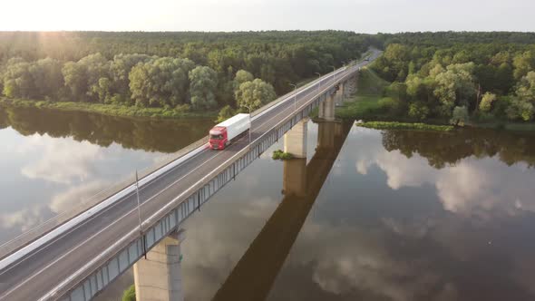 Aerial Drone Footage: Semi Truck with Cargo Trailer Passing Highway Bridge over the river