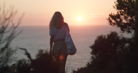 Woman Walks Towards the Beautiful Glow Sunset Enjoying the Sea View