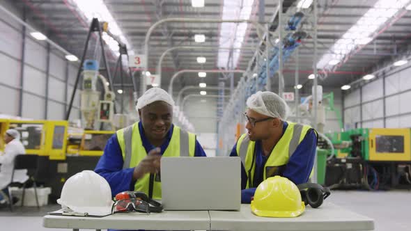 Warehouse workers using laptop in factory