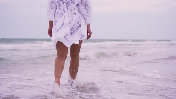 Girl Walks on the Beach on the Background of the Sea