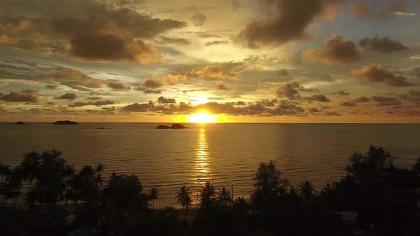 Aerial view of a calm tropical beach during orange sunset, Ko Chang, Thailand.