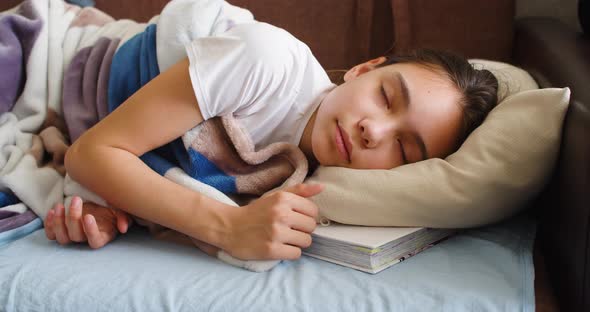 A Girl is Sleeping with a Book Under Her Pillow