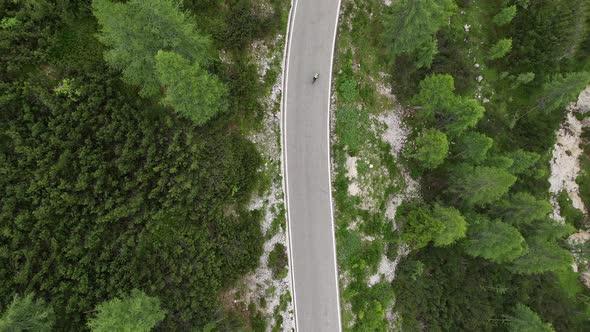 Flying above motorbikers and cyclists riding down a winding mountain road in the Dolomites