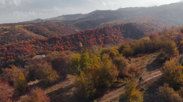 Aerial View of Cyclist in the Mountain Landscape with Autumn Forest