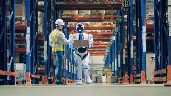 Warehouse Worker Working with Delivery Robot