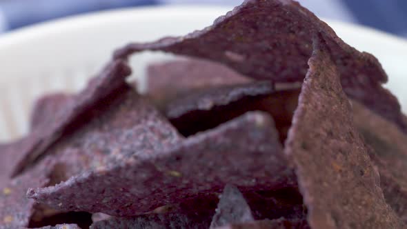 Rack focus on a bowl of blue nacho chips.