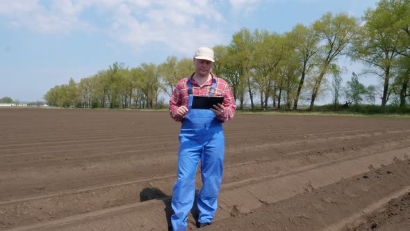 Farmer, Agronomist Stands Between Soil Rows on Farm Field, Testing Quality of Potatoe Planting By