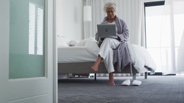 African american senior woman using laptop while sitting on the bed at home