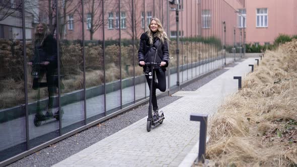 Blond Woman Riding Scooter and Making Face