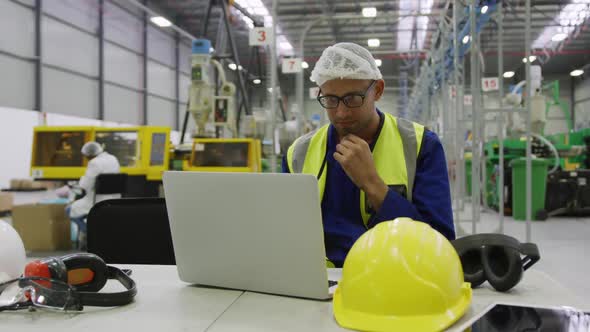 Warehouse worker using laptop in factory