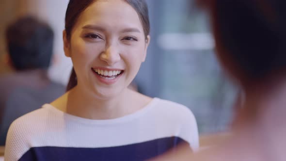 young attractive asian female smiling  positive conversation with friend at cafe